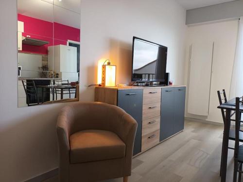 sala de estar con silla y tocador con TV en Appartement Le Grain de Sable, en Saint-Palais-sur-Mer