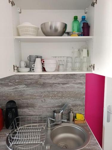 - un évier dans une cuisine avec une étagère et de la vaisselle dans l'établissement Appartement Le Grain de Sable, à Saint-Palais-sur-Mer