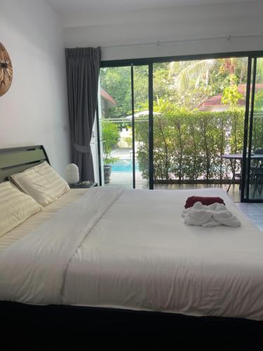 a bedroom with a large white bed and a large window at Lotus Bleu Resort & Restaurant in Rawai Beach
