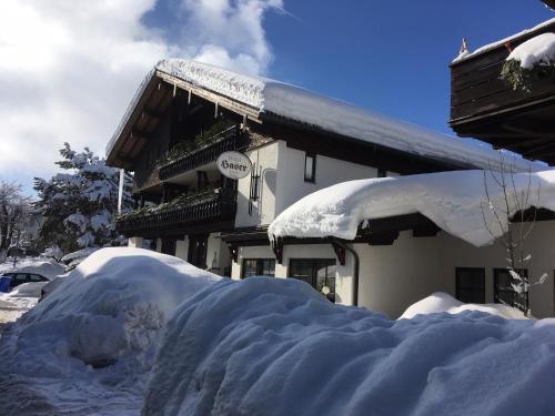 ein schneebedecktes Haus mit einem Schneehaufen in der Unterkunft Kur- und Ferienhotel Haser in Oberstaufen