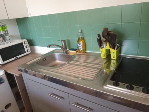 un comptoir de cuisine avec un évier et un micro-ondes dans l'établissement Beau appart à balcon vue Tour Eiffel & parking, à Paris