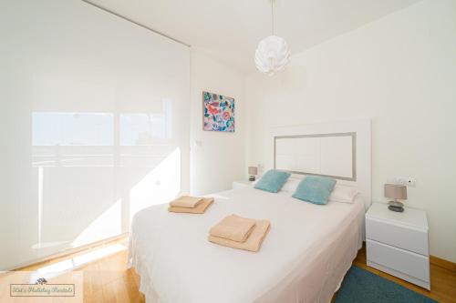 a white bedroom with a white bed with blue pillows at Luxury 2 Bed 2 Bath Apartment with pool in El Campello