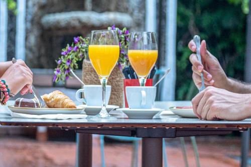 dos personas sentadas en una mesa con dos vasos de zumo de naranja en Hotel Casa Gardenia, en Barcelona