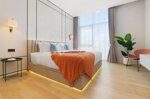 ein Schlafzimmer mit einem großen Bett mit einer orangefarbenen Decke in der Unterkunft Cielo by Kozystay - 2BR - Spacious - Kuningan in Jakarta