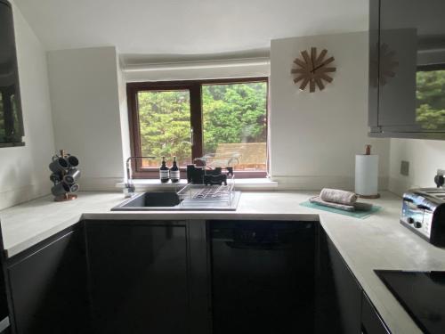 a kitchen with a sink and a window at The Coach House by Phoenix Premises - Hot Tub Fire Pit BBQ Log Burner Bar Games Room in Birmingham