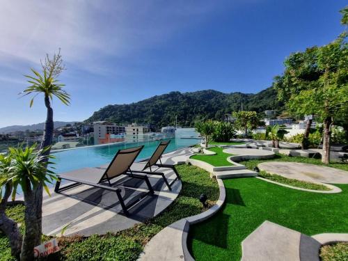 Mercure Phuket Patong Journeyhub في شاطيء باتونغ: اطلالة على مسبح وبجانبه كرسيين