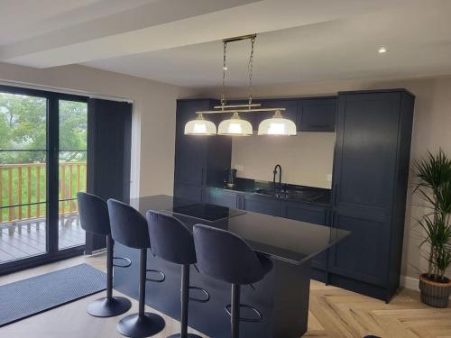 a kitchen with black cabinets and a island with bar stools at Shylo - Down At The Dales in Barry