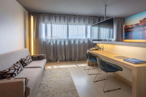 a living room with a couch and a desk with chairs at Barceló Malaga in Málaga