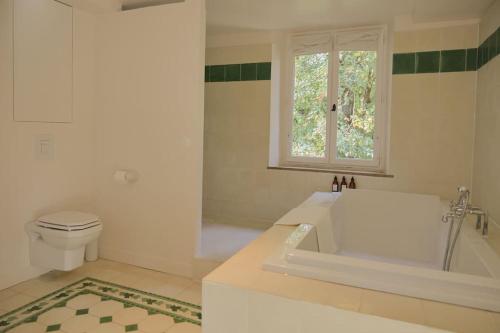 La salle de bains est pourvue d'une baignoire, de toilettes et d'une fenêtre. dans l'établissement Magnifique maison proche de Paris, La Prairie by Oasis House, à Égreville