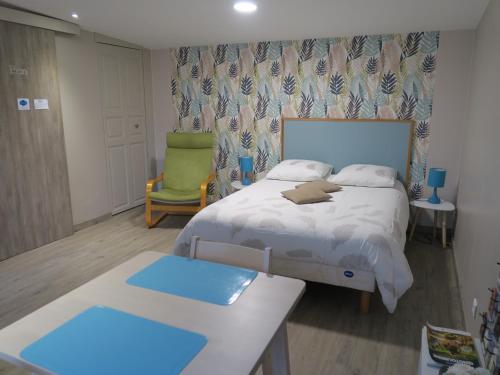 a bedroom with a bed and a green chair at Les Collinades de Chalons in Châlons-en-Champagne