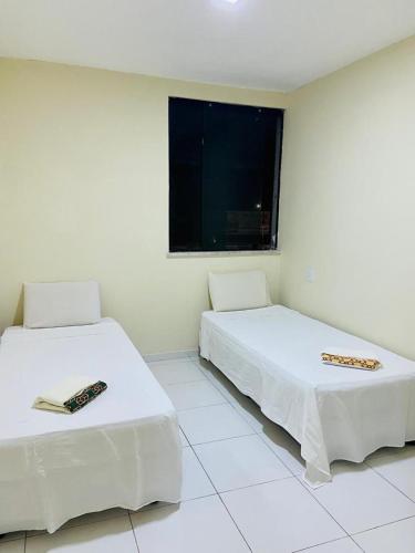 2 camas en una habitación blanca con ventana en Ape Atalaia, en Aracaju