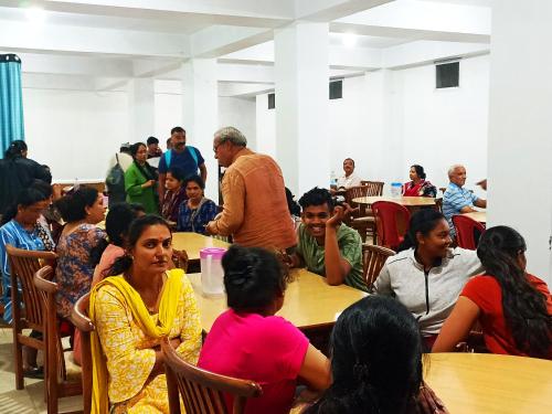 a group of people sitting at tables in a room at Hotel Bharmour View in Brāhmaur