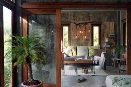 a living room with a couch and a palm tree at Boutique Jungle Villa - Baan ChaOm in Ko Lanta