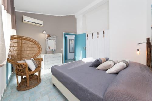una camera da letto con letto, cuscini e sedia di I Tre Golfi - Villa Iride a San Vito lo Capo