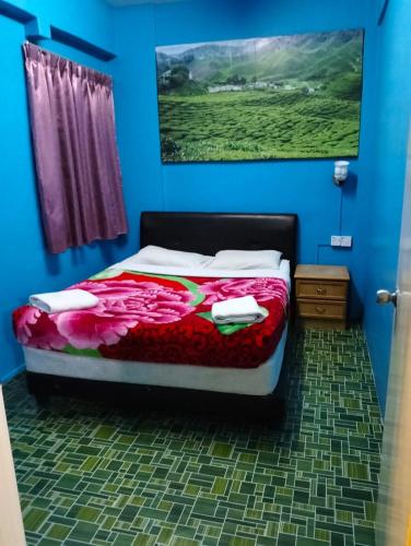 een slaapkamer met een bed met een schilderij aan de muur bij Orchid Haven islamic Homestay in Tanah Rata