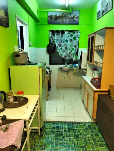 een keuken met groene muren en een tafel in een kamer bij Orchid Haven islamic Homestay in Tanah Rata