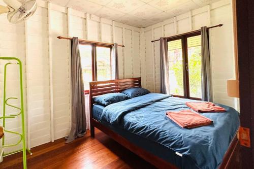 een slaapkamer met een bed met blauwe lakens en een raam bij Lamsai AC Sea House in Ko Yao Noi