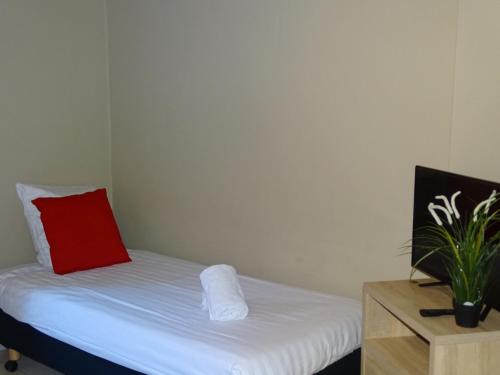 Cama pequeña con almohada roja y mesa en Room in Apartment - Condo Gardens Leuven - Student Studio Single en Leuven