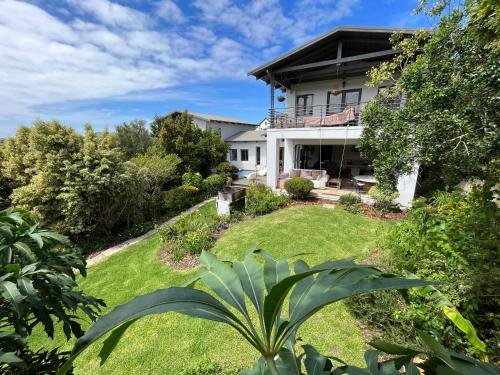 una casa con un patio verde delante de ella en Baha Sanctuary House - 3 Bedroom House with Pool, en Plettenberg Bay