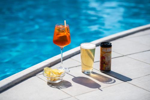 two drinks sitting next to a swimming pool at International Hotel & Suite in San Benedetto del Tronto