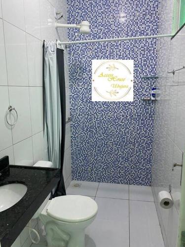 La salle de bains est pourvue de toilettes et d'un mur carrelé bleu. dans l'établissement Access House Ubajara:Sua casa na Serra Grande CE, à Ubajara