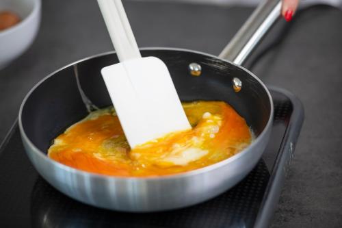 a spatula stirring a pot with orange food in it at International Hotel & Suite in San Benedetto del Tronto
