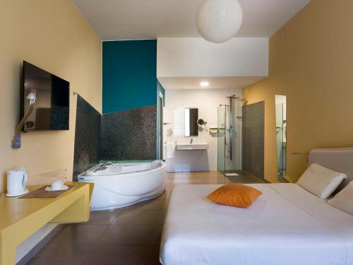 a bathroom with a bed and a bath tub in a room at ibis Styles Catania Acireale in Acireale