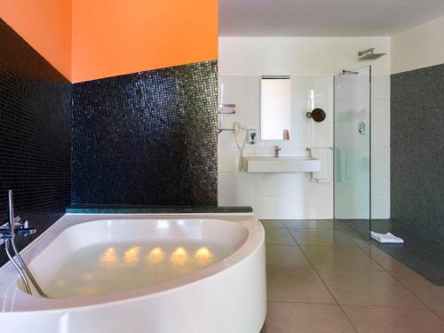 a bathroom with a tub and a glass shower at ibis Styles Catania Acireale in Acireale