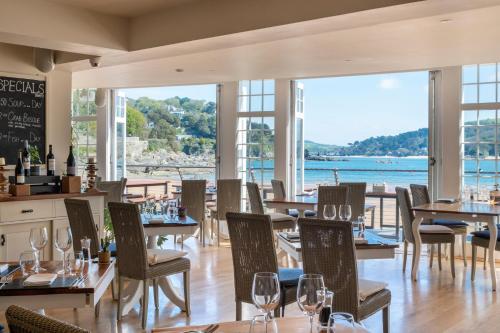 a restaurant with tables and chairs and a view of the water at South Sands Hotel in Salcombe