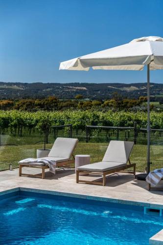 two lounge chairs and an umbrella next to a swimming pool at Pethick House in McLaren Vale