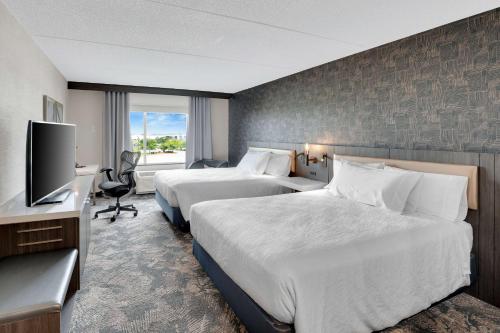 a hotel room with two beds and a flat screen tv at Hilton Garden Inn Toronto/Brampton in Brampton