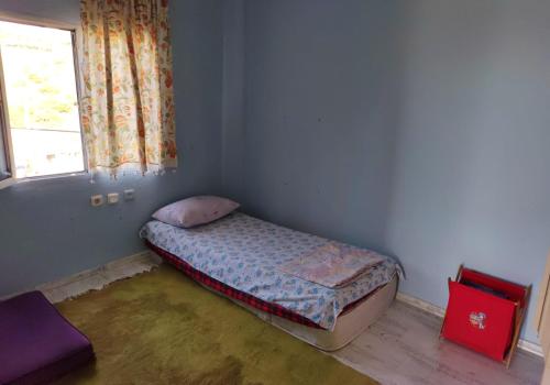 ein kleines Bett in einem Zimmer mit Fenster in der Unterkunft village house in Burunabat