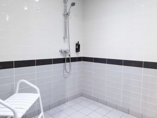 a bathroom with a shower with a bench in it at ibis Budget Villemomble in Villemomble