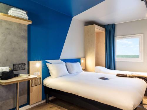 Habitación de hotel con cama y pared azul en ibis Budget Villemomble en Villemomble