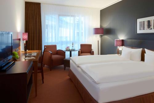 エアフルトにあるドリント ホテル アム ドーム エルフルトのベッド、デスク、椅子が備わるホテルルームです。