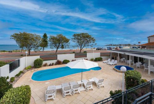 une terrasse avec une piscine, des chaises et un parasol dans l'établissement Quality Resort Sorrento Beach, à Perth