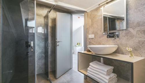 a bathroom with a glass shower and a sink at Monastery Suites Hotel in Oludeniz