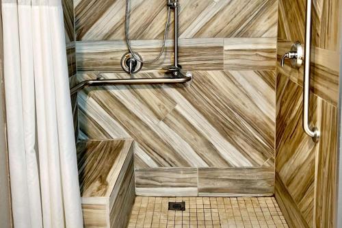 a bathroom with a shower with a wooden wall at Quality Inn & Suites Wisconsin Dells Downtown - Waterparks Area in Wisconsin Dells