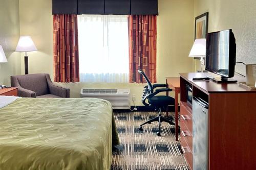 a hotel room with a bed and a desk with a television at Quality Inn & Suites Wisconsin Dells Downtown - Waterparks Area in Wisconsin Dells