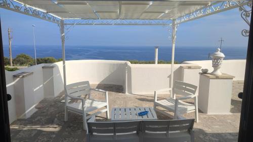duas cadeiras e uma mesa num alpendre com o oceano em Sofia em Castro di Lecce
