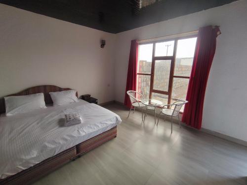 a bedroom with a bed and a window and a table at Stone rest house jebel shams in Al Ḩamrāʼ