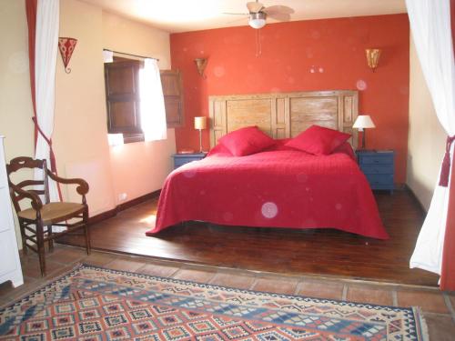 ein rotes Schlafzimmer mit einem Bett und einem Stuhl in der Unterkunft Beautifully renovated village house with spectacular views in Canillas de Albaida