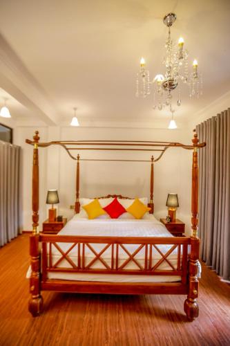 a bedroom with a wooden bed with yellow and red pillows at Covanro Sigiriya - Where Heritage Meets Luxury in Sigiriya