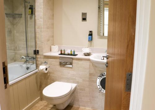 a bathroom with a toilet and a sink and a tub at South Sands Hotel in Salcombe