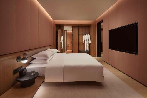 a bedroom with a large white bed and a flat screen tv at TAOXICHUAN Hotel in Jingdezhen