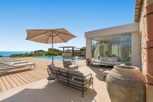 a patio with benches and an umbrella and a pool at Al Nair in Marina di Modica