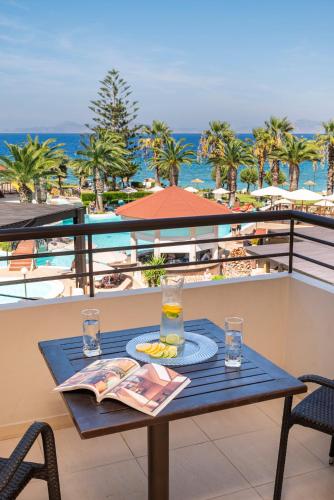 a table on a balcony with a drink and a newspaper at D'Andrea Mare Hotel in Ialyssos