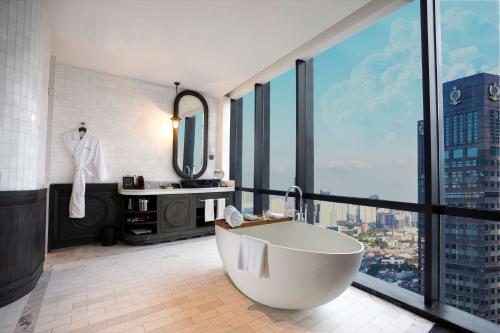 a bathroom with a tub and a large window at The Orient Jakarta, a Royal Hideaway Hotel in Jakarta