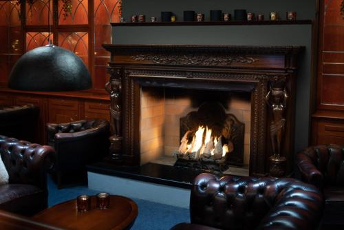 a fireplace in a room with leather chairs and a table at Quality Hotel Sundsvall in Sundsvall