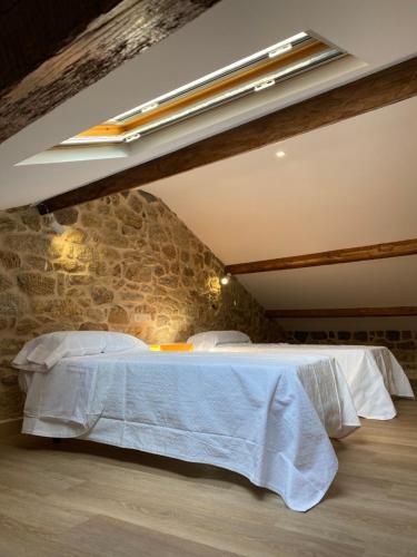 a bed in a room with a stone wall at CASA do CAMPO Lestrove in Padrón